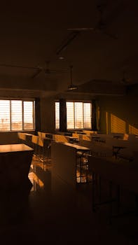 Warm light fills an empty classroom, highlighting desks at sunset.