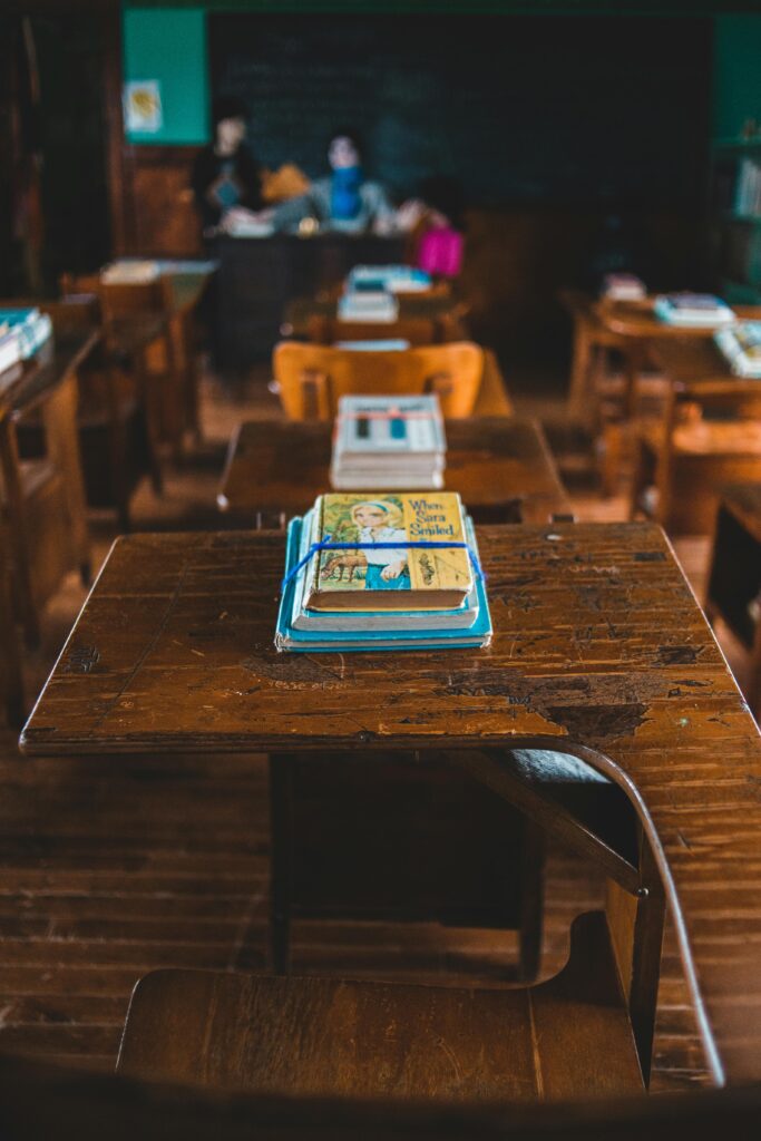 Vintage classroom setting featuring wooden desks and a stack of classic books in focus.